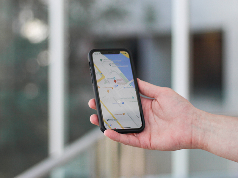 a hand holds an iphone with google maps on the screen 