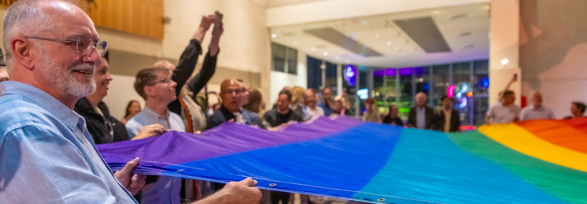 Representatives of Brisbane Pride and LGBTQIA+ community holding the Gilbert Baker flag at Queensland Museum